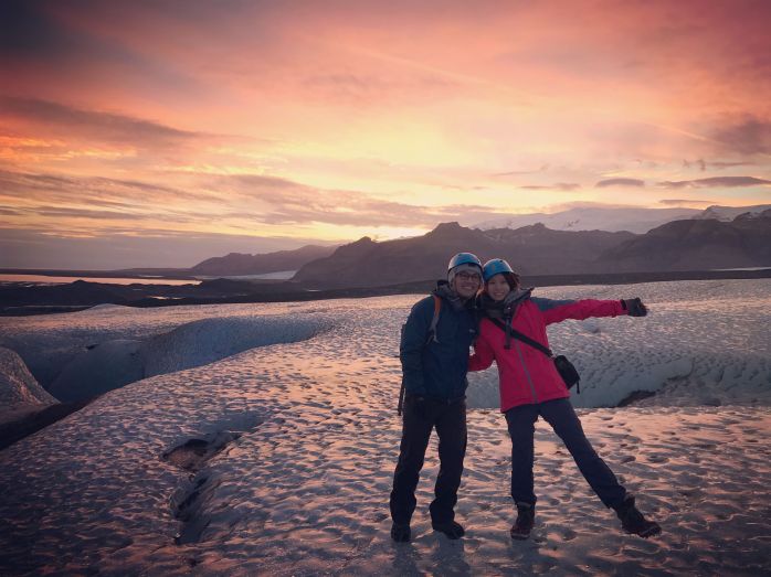 People standing in snow during sunset.